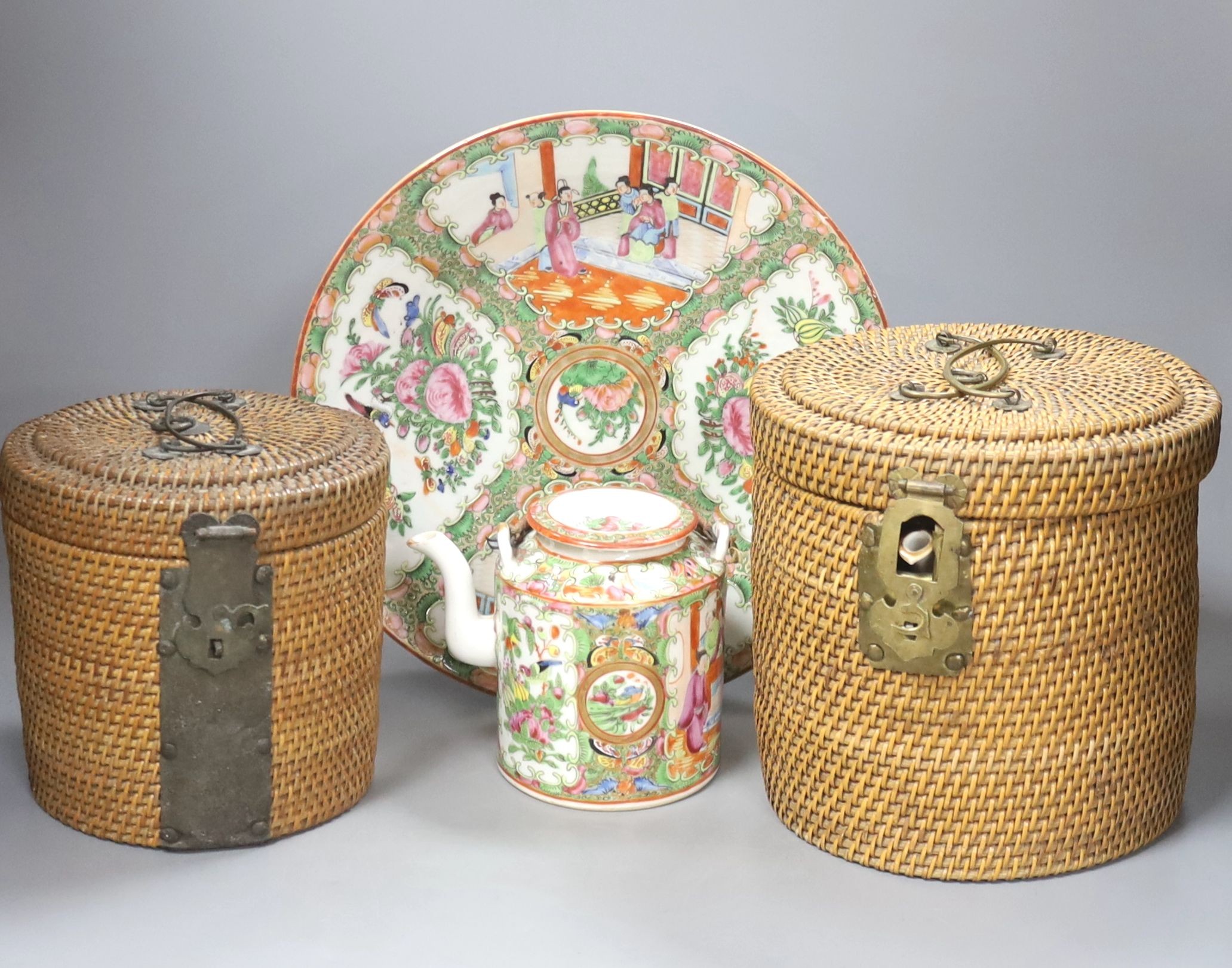 Three late 19th/early 20th century Chinese famille teapots, two in baskets and a similar dish, dish 29.5 cms diameter.